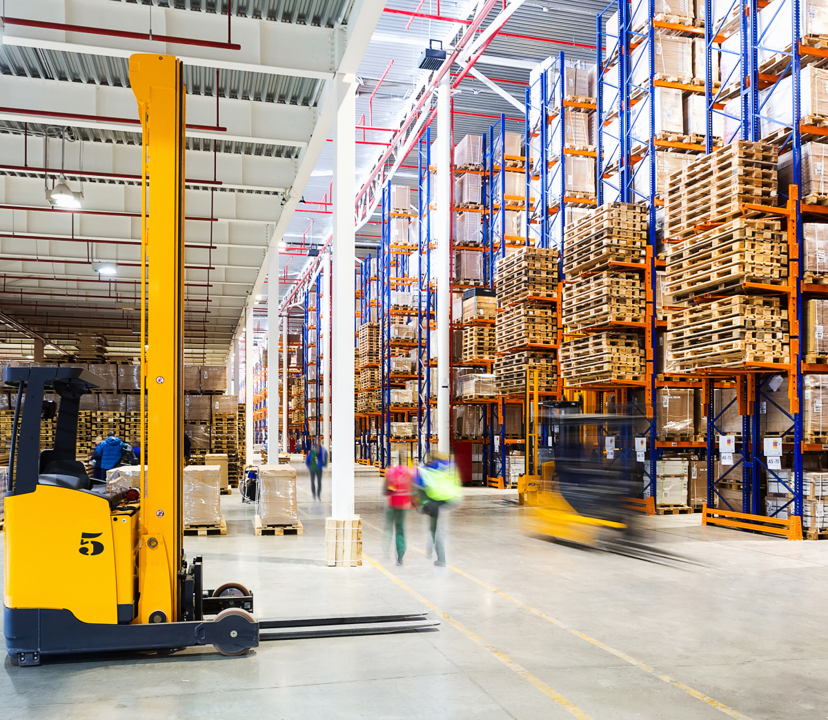 Softeon Recognized in 2025 Gartner® Critical Capabilities for Warehouse Management Systems Report Across All Warehouse Operation Levels 8 Interior of a busy warehouse with shelves of goods and a stationary forklift.